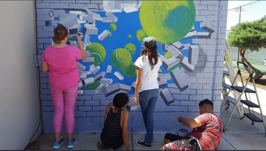 Youth painting a mural on a wall.