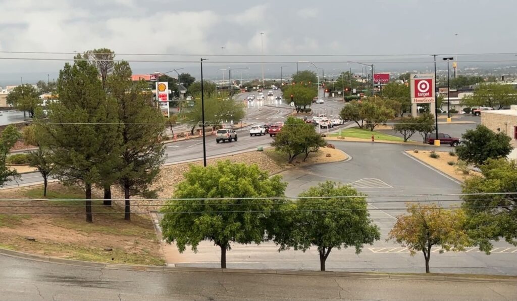 A parking lot and street wet from rain.