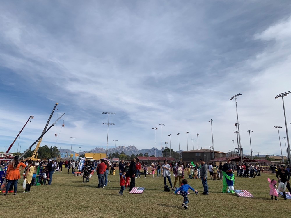 a photo of a park with children in halloween costumes getting candy