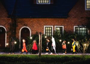 a photo of a group of children wearing halloween costumes while trick or treating.
