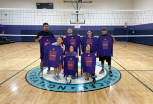 People holding t-shirts on a volleyball court.